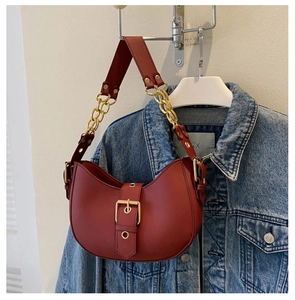Détail du sac hobo bordeaux avec boucle dorée sur fond de veste en jean bleu classique