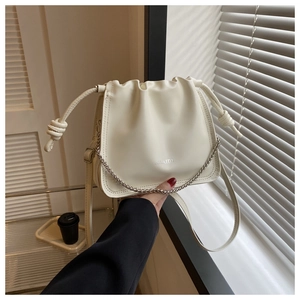 Dettaglio di borsa a secchiello bianca con coulisse elegante e catena decorativa chic.