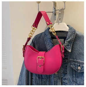 Détail du sac demi-lune rose fuchsia avec chaîne dorée sur fond de veste en jean