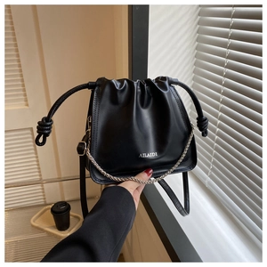 Dettaglio borsa a secchiello in pelle PU nera, coulisse con catena e manico eleganti.