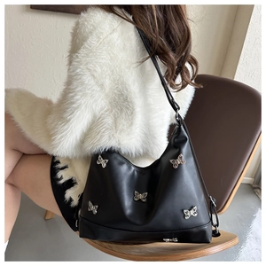 Detail einer schwarzen Hobo-Tasche aus Leder mit silbernen Schmetterlingsanhängern
