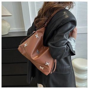 Detailansicht der braunen Ledertasche mit silbernen Schmetterlingsanhängern am Model