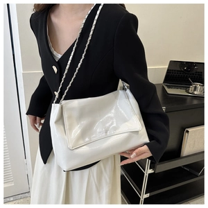 Détail du sac à bandoulière blanc brillant avec chaîne argentée et logo sur le rabat