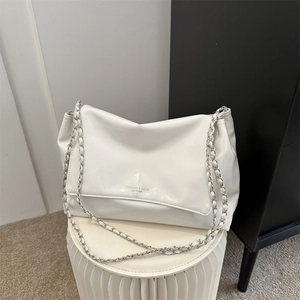 Sac fourre-tout minimaliste en cuir blanc avec bandoulière chaîne sur un socle blanc