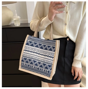 Detailed view of canvas tote bag featuring navy blue geometric patterns and beige handles