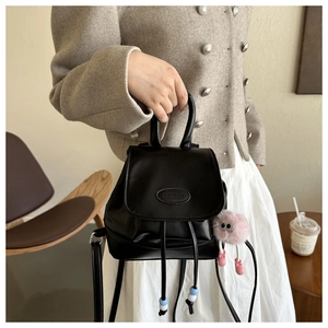 Detail of black mini drawstring backpack with PAUTOR logo and pink plush doll charm