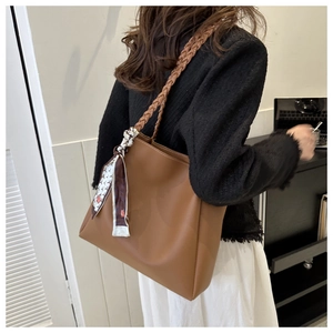 Detail view of brown faux leather tote bag with woven strap and decorative scarf