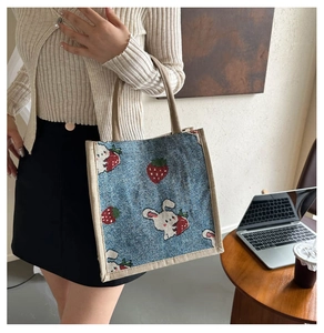 Detail of blue canvas tote bag featuring cute rabbit and strawberry jacquard patterns