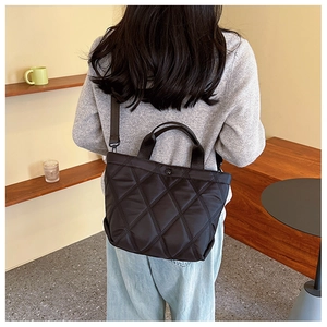 Gros plan sur un sac seau noir matelassé à motif losanges en tissu résistant à l'eau