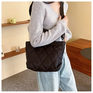 Détail d'un grand sac cabas noir matelassé avec coutures carrées et bandoulière en nylon