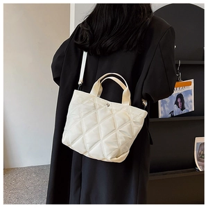 Détail du sac cabas matelassé blanc avec surpiqûres en losanges sur manteau noir