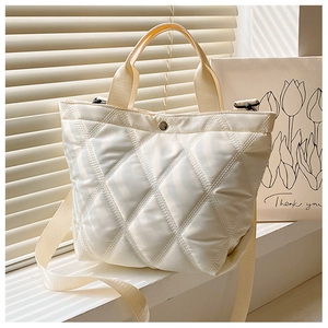 Détail du sac seau matelassé crème en nylon avec motif de losanges et bandoulière