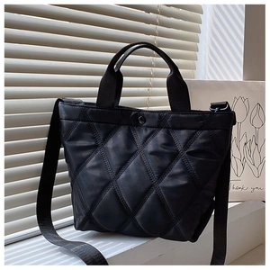 Détail du sac à main noir matelassé à motif losanges avec bandoulière et matière en nylon