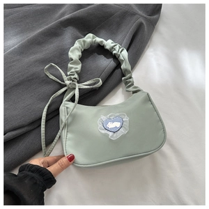 Détail du sac vert clair avec poignée froncée et écusson cœur lapin brodé