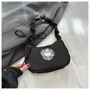 Détail du sac sous l'aisselle noir avec patch lapin à carreaux bleus et poignée froissée