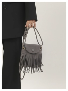 Détail du sac bandoulière gris en daim à longues franges et finitions dorées sur mannequin