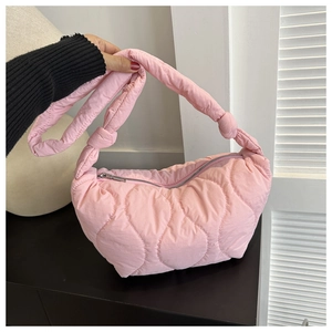 Detail of pink quilted shoulder bag featuring a knotted strap and wavy cloud texture