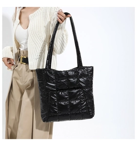 Detail of the black quilted tote bag featuring glossy lattice stitching and padded handles