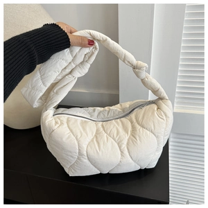 Detail of white quilted dumpling bag featuring puffy wave stitching and knotted strap