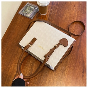 Gros plan d'un sac à main beige matelassé avec poignées brunes sur bureau bois