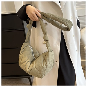 Detail of light green quilted crescent shoulder bag with knotted strap and zipper
