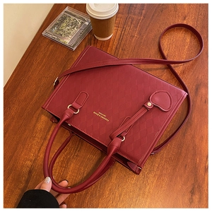 Détail du sac matelassé bordeaux avec pendentif cœur sur un fond en bois