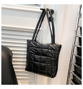 Detail of black quilted tote bag with puffer texture hanging on a door handle