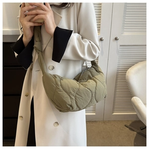 Detail of olive green quilted puffy hobo bag with wave stitching and knot strap