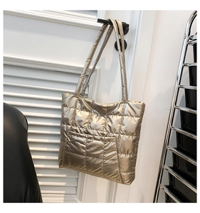 Detail of gold metallic quilted tote bag featuring a square stitch texture and side pocket