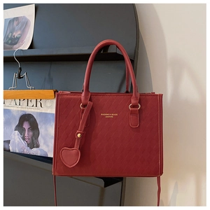 Détail du sac cabas matelassé bordeaux avec pendentif en cœur et lettrage doré