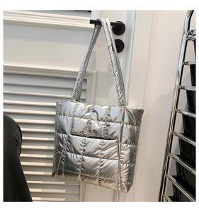 Close-up of a silver puffer tote bag with quilted squares hanging on a white door handle