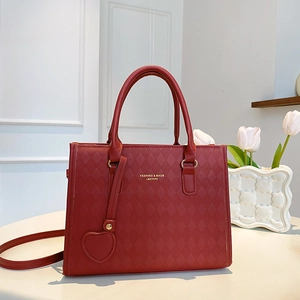 Sac fourre-tout rouge matelassé grande capacité avec breloque cœur sur un bureau