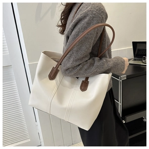Side view of white lychee texture tote bag with brown handles on model's shoulder