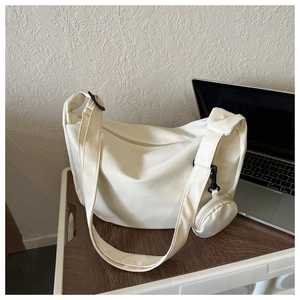 Close-up of woven canvas texture and small coin purse on beige crossbody dumpling bag