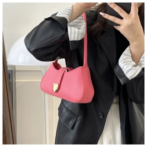 Detail view of pink leather shoulder bag with a gold heart clasp and sleek design
