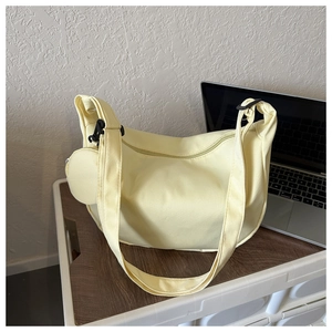 Detail of light yellow canvas crescent bag with detachable round pouch and wide shoulder strap
