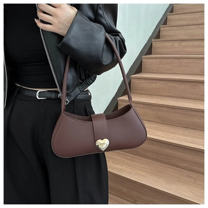 Detail of dark brown faux leather crescent bag with golden heart buckle on a model