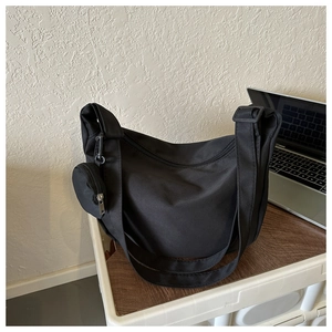 Detail of black nylon shoulder bag with adjustable wide strap and detachable round pouch