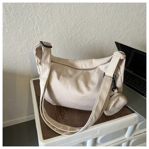 Detail of beige canvas crossbody bag with small round coin purse and wide strap