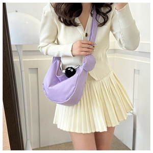Detail of lavender hobo bag featuring a round coin purse and a black plush charm