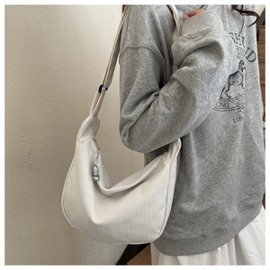 Detail of white corduroy half-moon bag featuring textured fabric and adjustable strap
