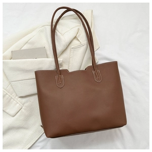 Brown faux leather tote bag with white contrast stitching and asymmetric edge design