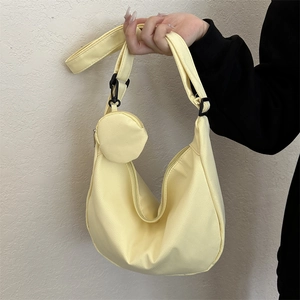 Light yellow nylon crescent crossbody bag with adjustable strap and mini round pouch charm