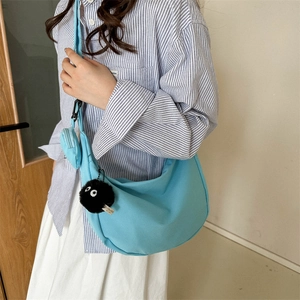 Sky blue canvas crescent shoulder bag with wide strap and black soot sprite charm
