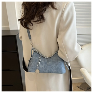 Detail of blue denim shoulder bag with silver chunky chain and round metal charm