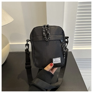 Close-up of black nylon shoulder bag featuring the HELLO WEEKEND text label and zipper detail
