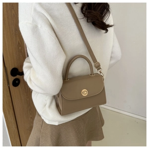 Detail view of khaki leather square bag with golden twist lock and adjustable shoulder strap