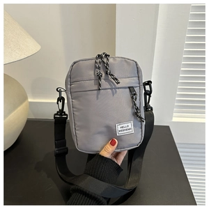 Detailed view of grey nylon crossbody phone bag with Hello Weekend label and wide strap