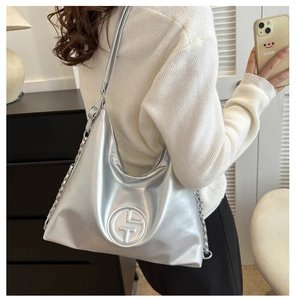 Détail du sac cabas argenté métallisé avec logo circulaire embossé et bandoulière chaîne