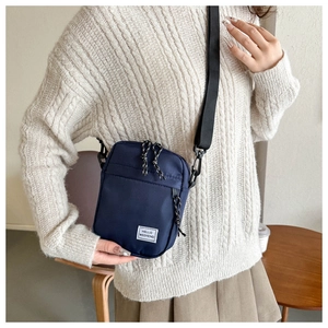 Detail of dark blue nylon crossbody bag with dual zippers and Hello Weekend tag